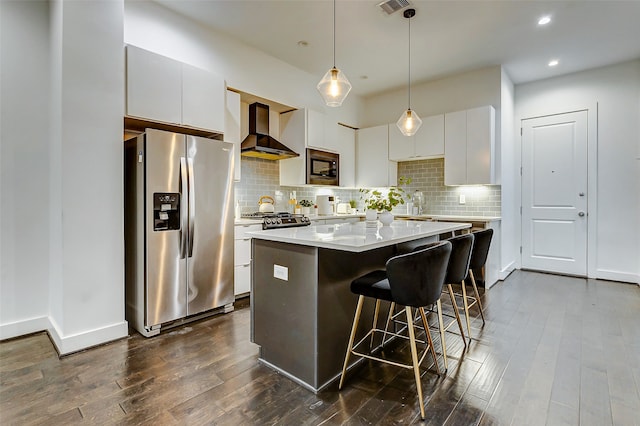 kitchen with a kitchen island, white cabinetry, wall chimney range hood, and stainless steel appliances