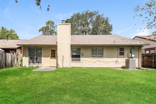 rear view of property featuring a lawn and central AC unit