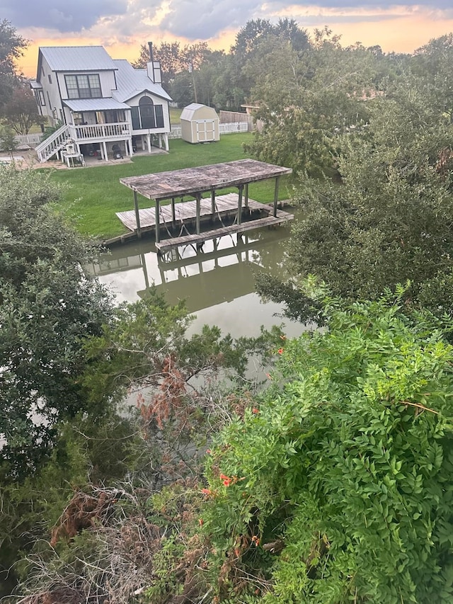 view of home's community with a shed, a dock, and a lawn