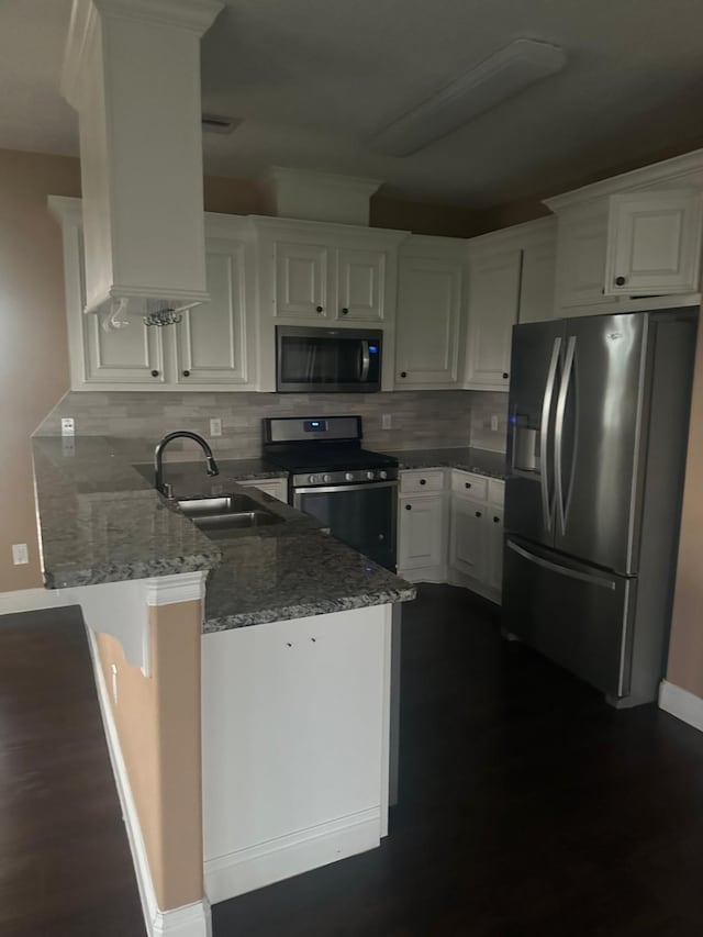 kitchen featuring dark stone countertops, white cabinets, appliances with stainless steel finishes, and kitchen peninsula