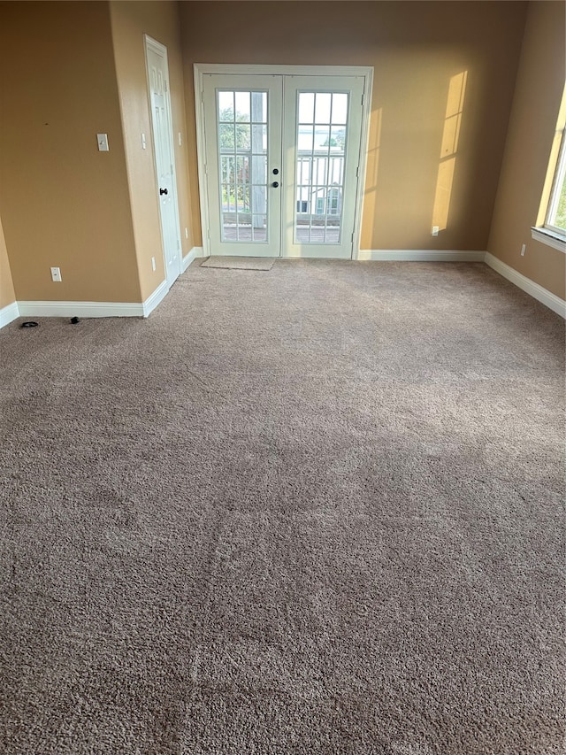 carpeted spare room featuring a healthy amount of sunlight and french doors