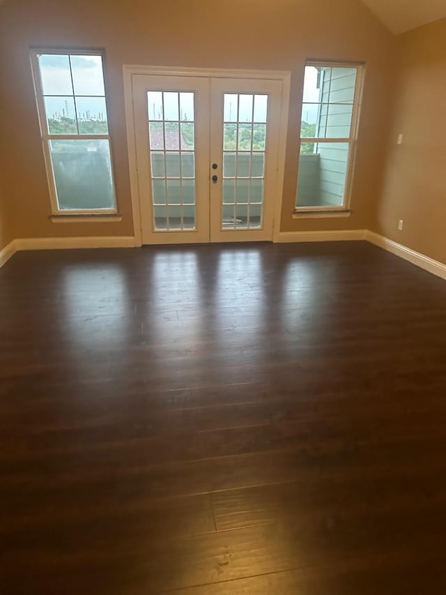 empty room featuring lofted ceiling, dark hardwood / wood-style floors, and french doors