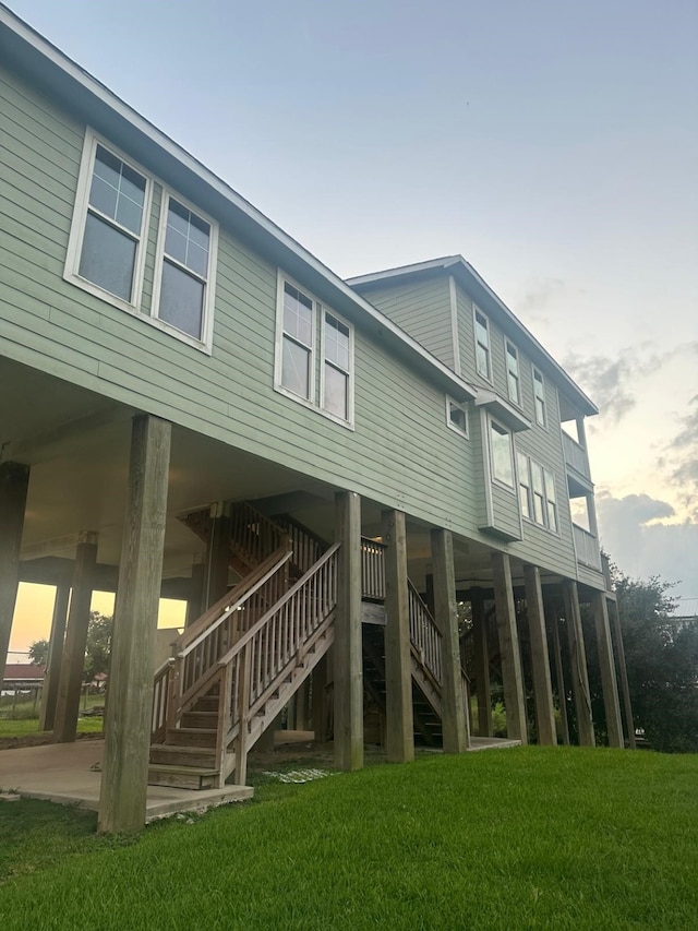 back house at dusk featuring a lawn