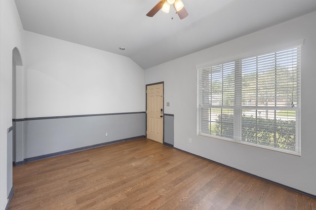 spare room with wood-type flooring, vaulted ceiling, and plenty of natural light