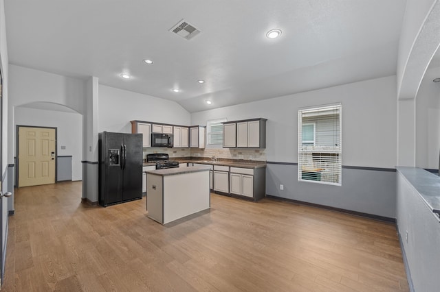 kitchen featuring gray cabinetry, black appliances, light wood-type flooring, a center island, and lofted ceiling