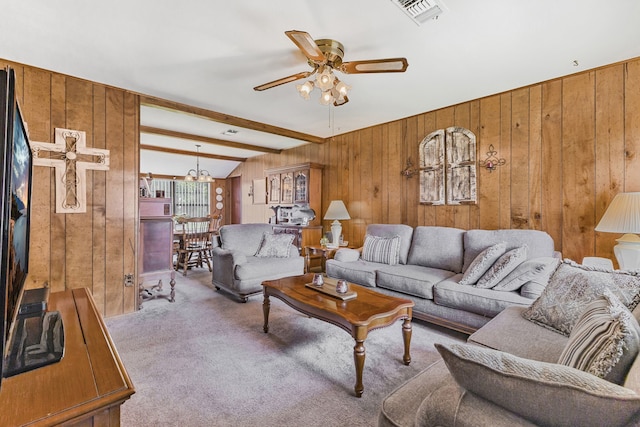 carpeted living room featuring beam ceiling, ceiling fan, and wood walls