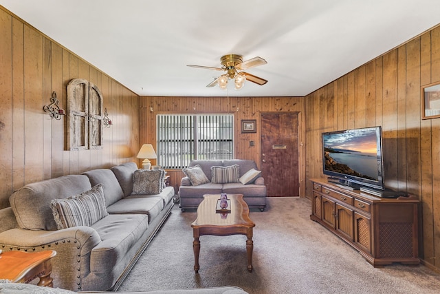 carpeted living room featuring ceiling fan and wooden walls