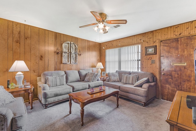 carpeted living room featuring ceiling fan and wood walls