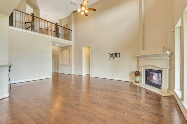 unfurnished living room featuring ceiling fan, a towering ceiling, and dark hardwood / wood-style flooring