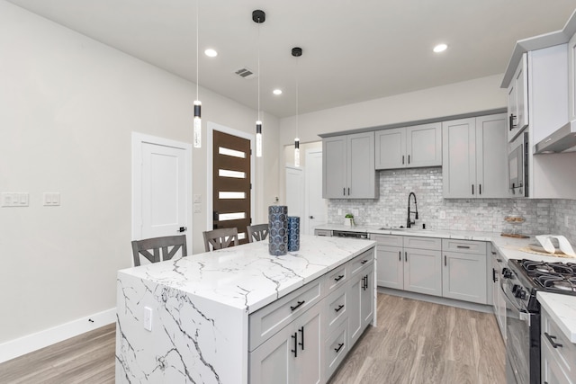 kitchen with gray cabinetry, stainless steel appliances, sink, and a kitchen island