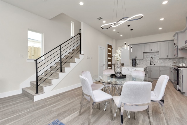 dining area with light hardwood / wood-style floors, sink, and a chandelier