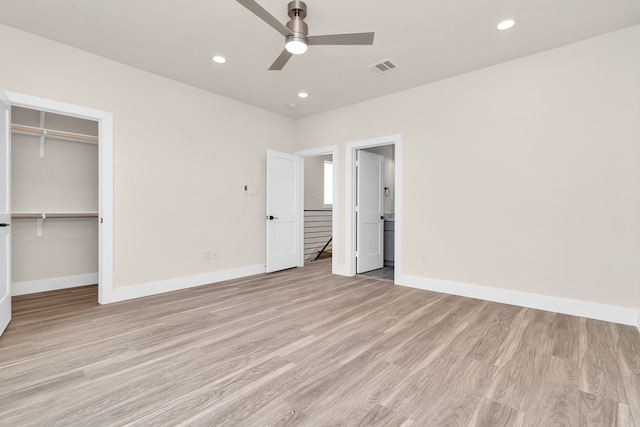 unfurnished bedroom featuring ceiling fan, light wood-type flooring, a closet, and a walk in closet