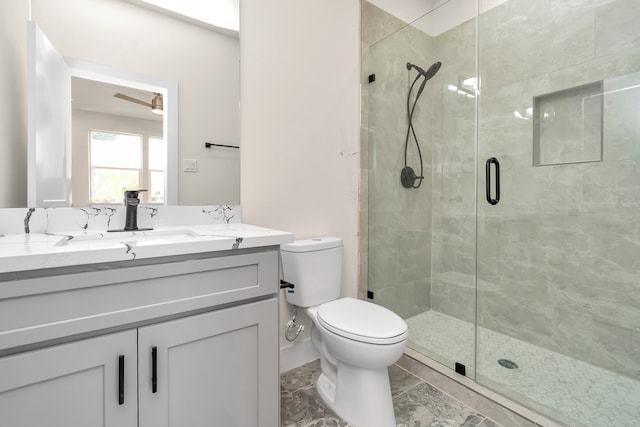 bathroom with ceiling fan, a shower with door, vanity, and toilet