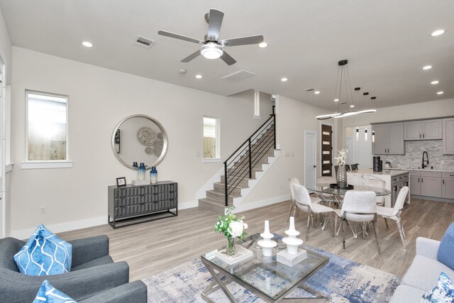 living room featuring light wood-type flooring, ceiling fan, and sink