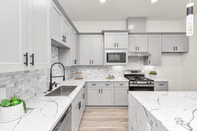 kitchen with pendant lighting, stainless steel appliances, light stone countertops, and sink