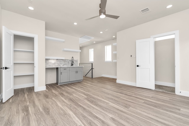 kitchen featuring light hardwood / wood-style floors, tasteful backsplash, gray cabinets, ceiling fan, and sink