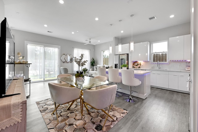 dining room with light wood-type flooring, sink, and ceiling fan