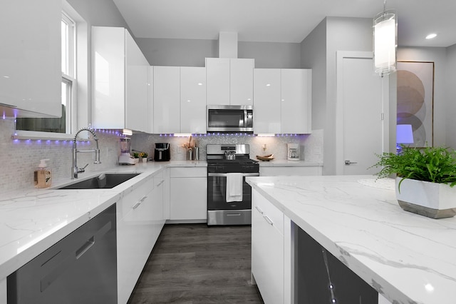 kitchen featuring pendant lighting, appliances with stainless steel finishes, decorative backsplash, and white cabinetry