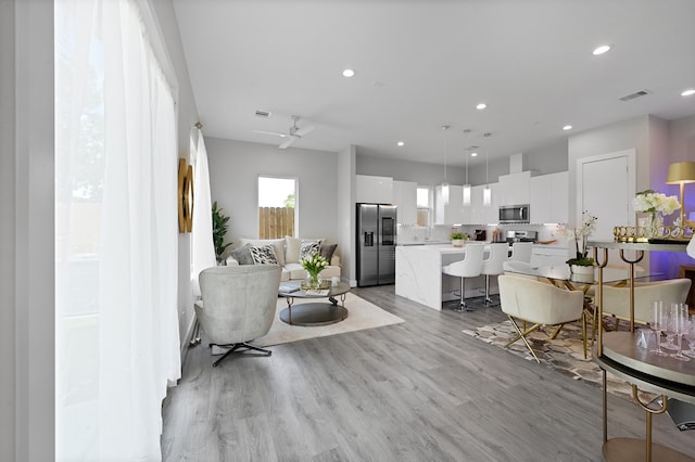 living room with light hardwood / wood-style floors and ceiling fan