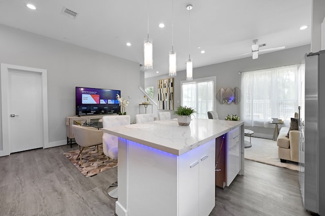 kitchen with a center island, hanging light fixtures, stainless steel refrigerator, light hardwood / wood-style flooring, and ceiling fan