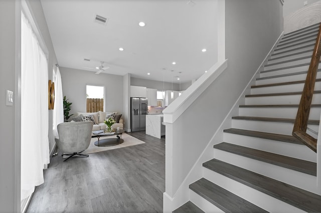 staircase with ceiling fan and hardwood / wood-style floors