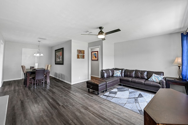 living room with ceiling fan with notable chandelier and dark hardwood / wood-style flooring