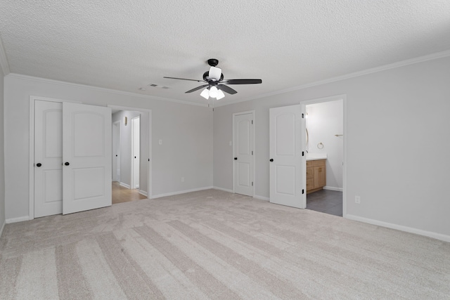 unfurnished bedroom featuring a textured ceiling, light carpet, ensuite bathroom, ornamental molding, and ceiling fan