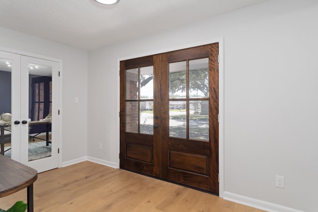 entrance foyer with a textured ceiling, light hardwood / wood-style floors, and french doors