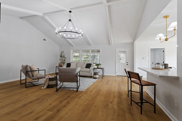 living room featuring a chandelier, a textured ceiling, beamed ceiling, hardwood / wood-style flooring, and high vaulted ceiling