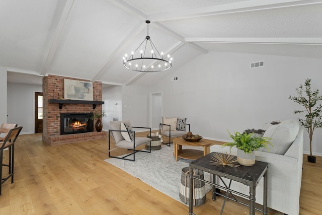 living room featuring vaulted ceiling with beams, an inviting chandelier, a fireplace, and hardwood / wood-style flooring