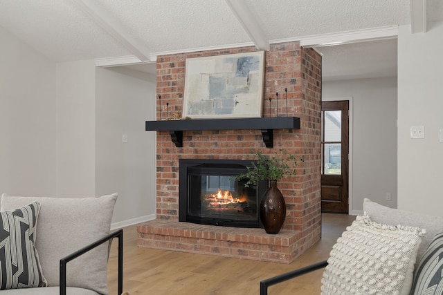 living room featuring a textured ceiling, beamed ceiling, hardwood / wood-style flooring, and a fireplace