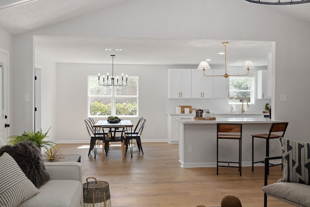 interior space with sink, light hardwood / wood-style flooring, and vaulted ceiling