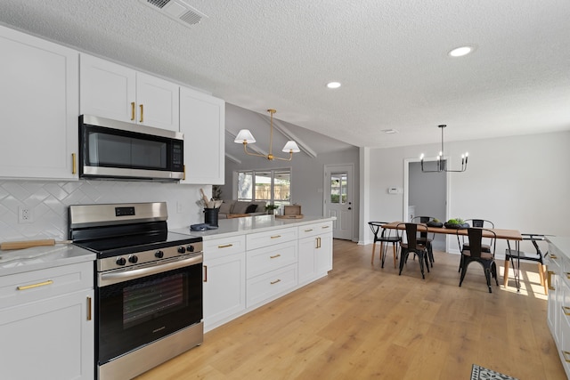 kitchen with an inviting chandelier, white cabinets, appliances with stainless steel finishes, and decorative light fixtures