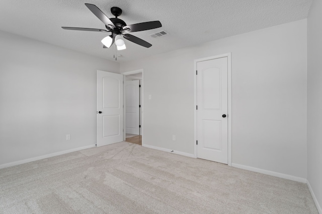 unfurnished bedroom featuring ceiling fan, a textured ceiling, and light carpet