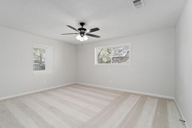 unfurnished room with ceiling fan, light colored carpet, and a textured ceiling