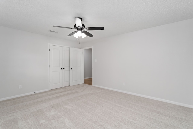 empty room featuring a textured ceiling, light carpet, and ceiling fan