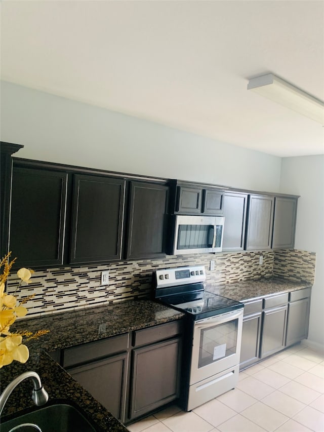 kitchen featuring decorative backsplash, appliances with stainless steel finishes, sink, and dark stone countertops