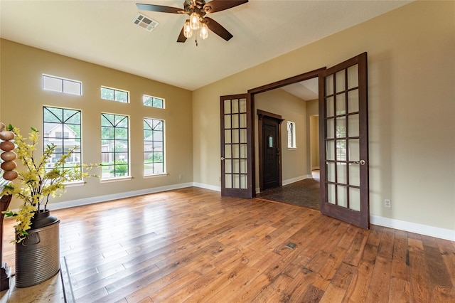 empty room featuring wood-type flooring, lofted ceiling, ceiling fan, and french doors