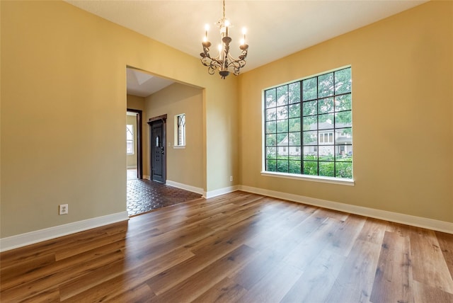 unfurnished room featuring an inviting chandelier and hardwood / wood-style floors