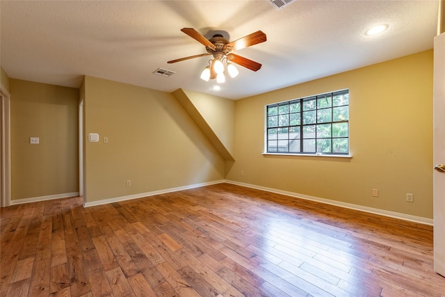 spare room with ceiling fan, a textured ceiling, and light hardwood / wood-style flooring