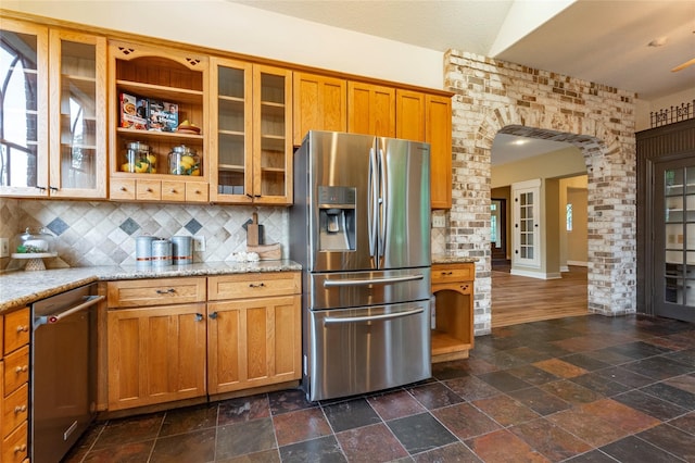 kitchen with decorative backsplash, light stone counters, and appliances with stainless steel finishes