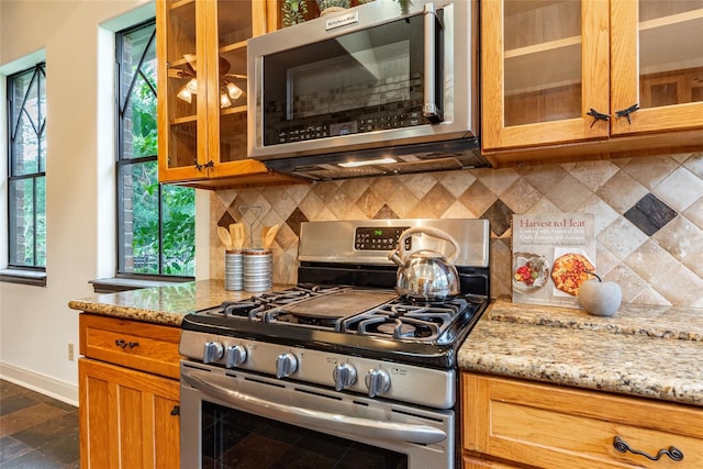 kitchen featuring light stone counters, stainless steel appliances, and tasteful backsplash