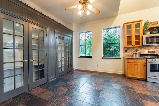 kitchen with light stone counters, ceiling fan, french doors, backsplash, and stainless steel appliances