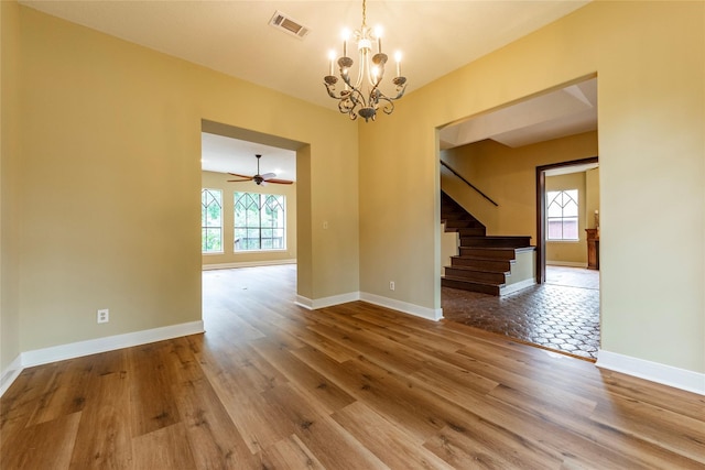 spare room with wood-type flooring and ceiling fan with notable chandelier