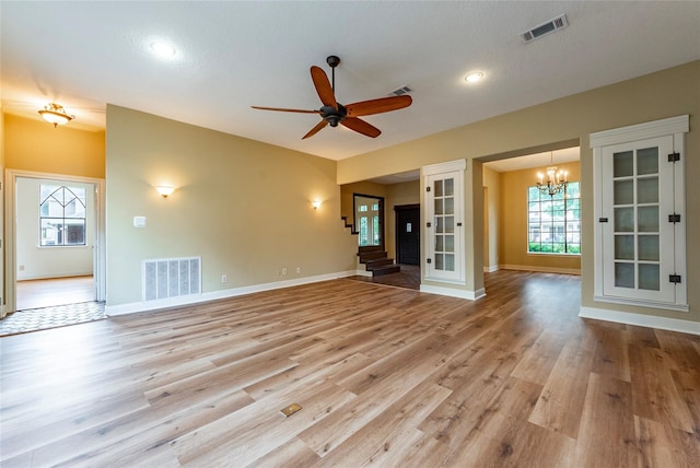 spare room featuring a textured ceiling, ceiling fan with notable chandelier, and light hardwood / wood-style flooring