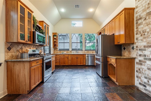 kitchen with vaulted ceiling, light stone counters, backsplash, stainless steel appliances, and sink