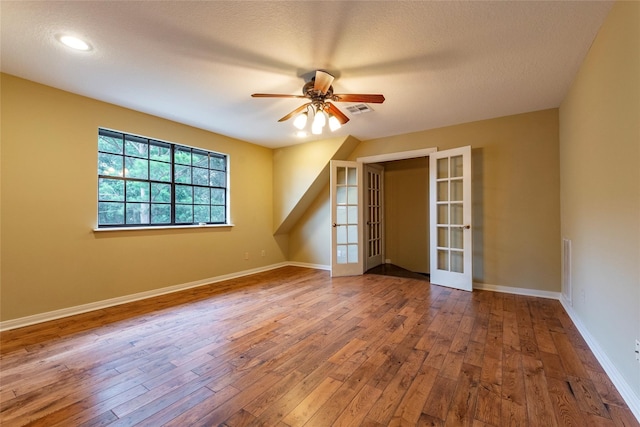 unfurnished bedroom with ceiling fan, hardwood / wood-style flooring, french doors, and a textured ceiling