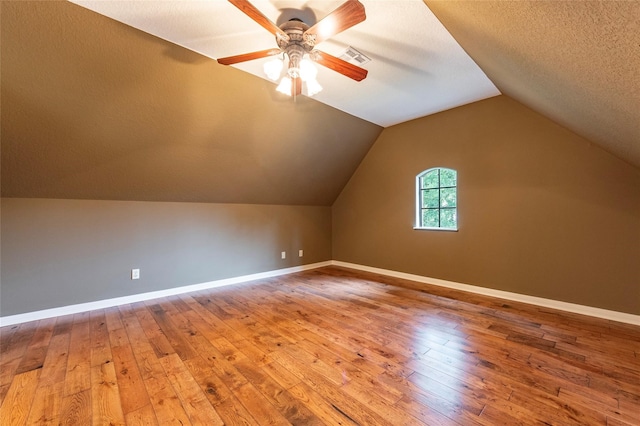 additional living space featuring ceiling fan, a textured ceiling, lofted ceiling, and hardwood / wood-style floors