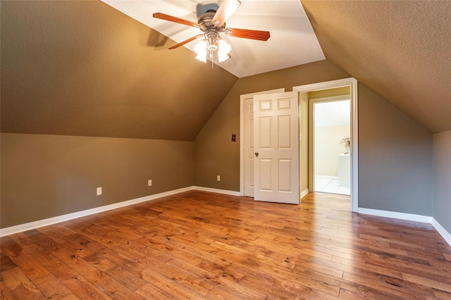 bonus room featuring a textured ceiling, lofted ceiling, hardwood / wood-style floors, and ceiling fan