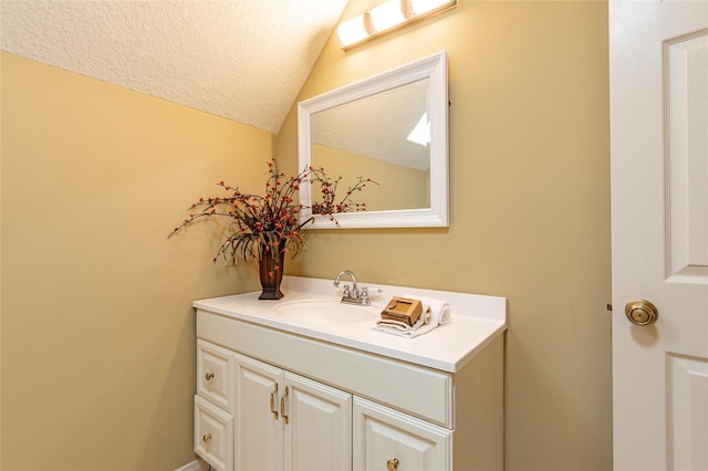 bathroom with lofted ceiling, a textured ceiling, and vanity